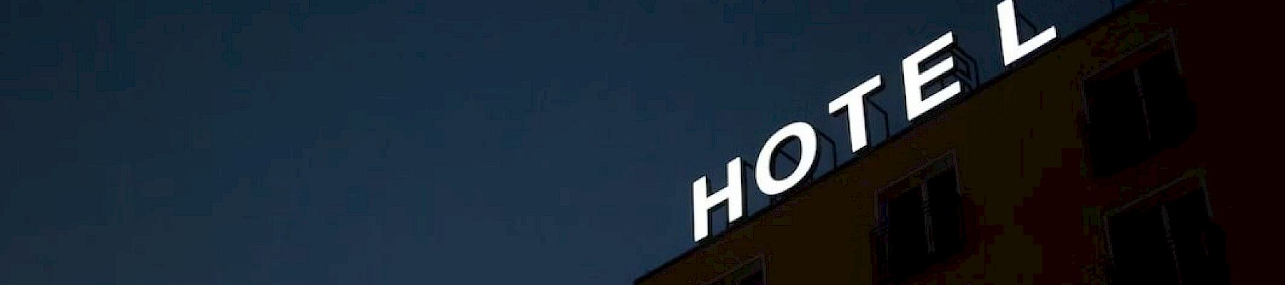 A building with a sign says "HOTEL" against a dark sky, with letters illuminated.