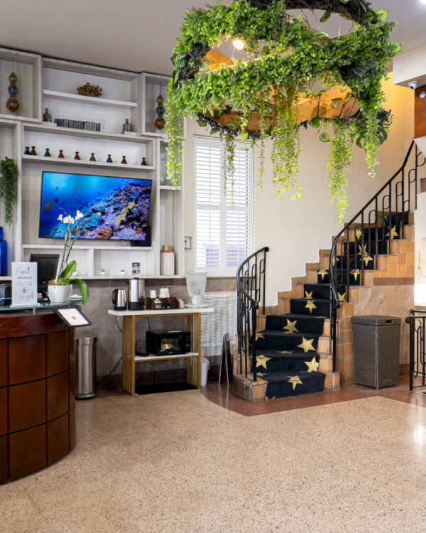 Bright lounge with green vines over a staircase, a cozy fireplace nook, and seating in front of a hookah-themed screen.