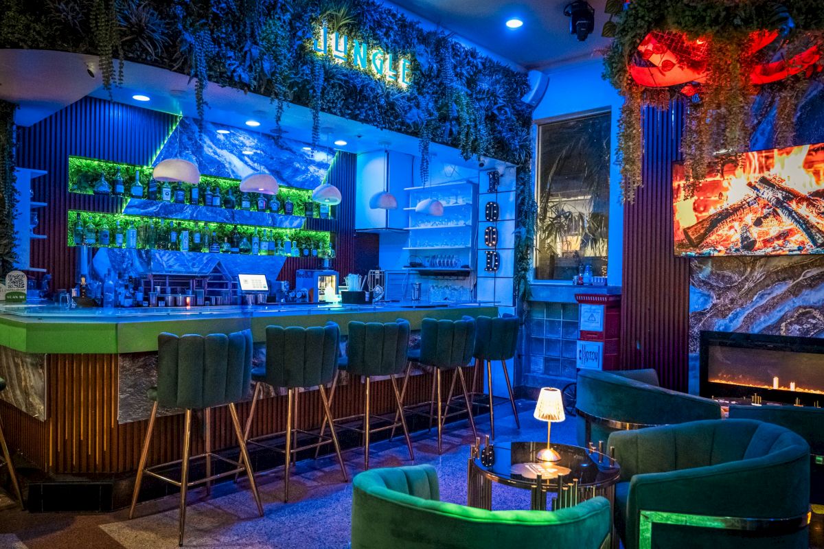 A dimly lit bar with green chairs and a TV on the wall